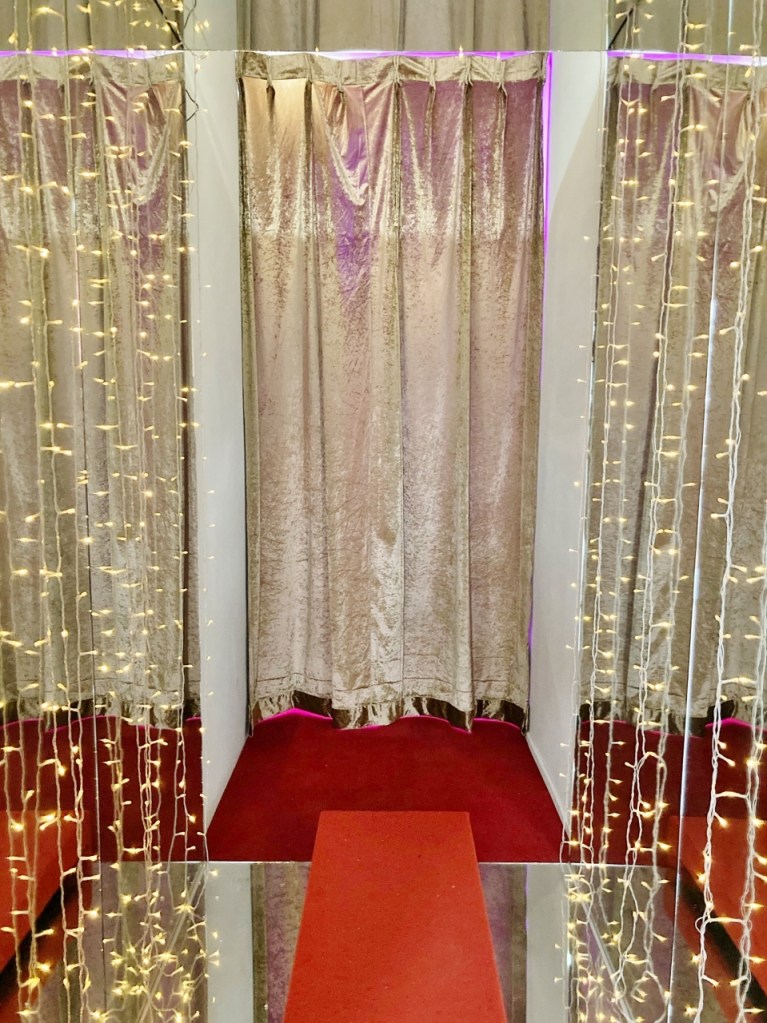 Walkway with fairy lights and mirrors on both sides of the wall at Enchanted Manor