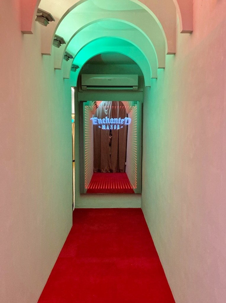 Corridor with mirror at the end with changing neon lights at Enchanted Manor