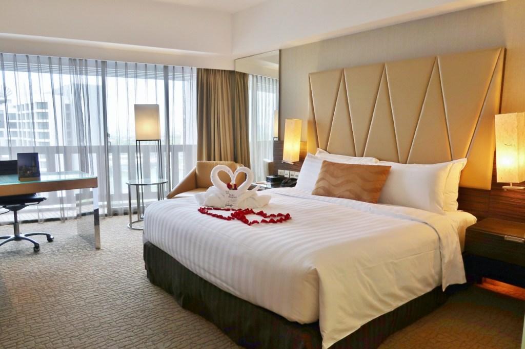Premier room with rose petals and swan towels on the bed at PARKROYAL Collection Marina Bay Hotel