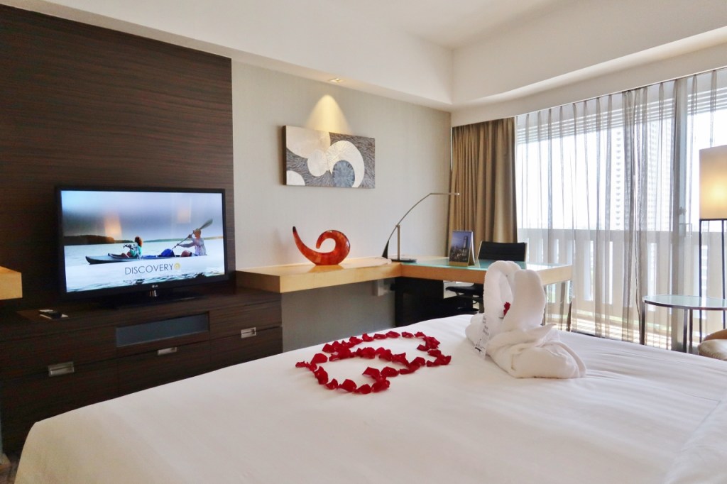 Premier room with rose petals and swan towels on the bed at PARKROYAL Collection Marina Bay Hotel