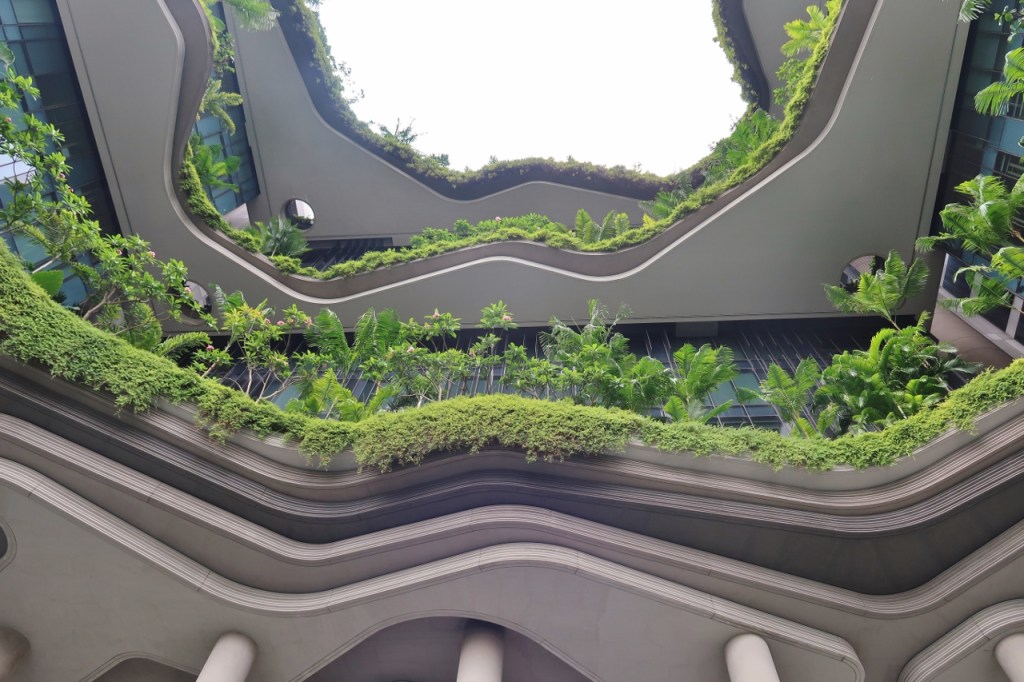 Skyward view of PARKROYAL COLLECTION Pickering Hotel's building facade from the garden path