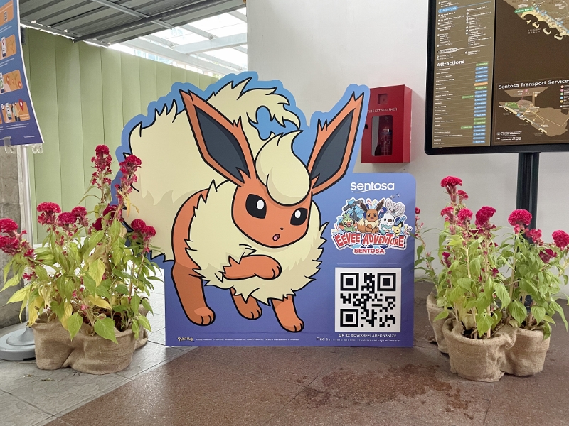 An Eevee Adventure Mission panel with Flareon and a QR code located at Sentosa's Imbiah monorail station